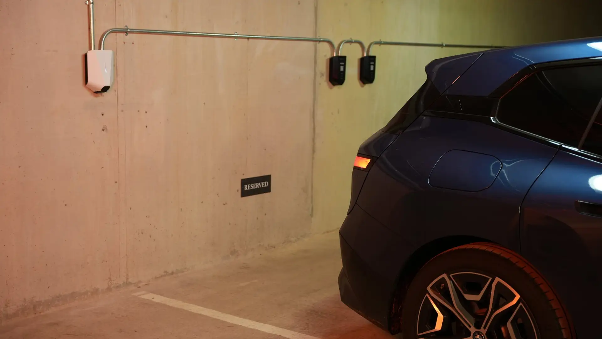 Two Easee chargers on the wall of an underground car park with an electric BMW in a reserved bay