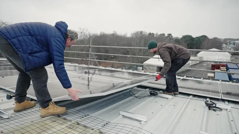 Two Vanadium installers carrying a panel into position on the roof