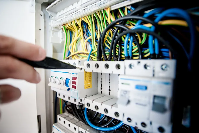 Electrician tightening a terminal on a consumer unit full of RCBOs