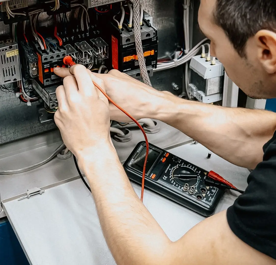 Electrician testing circuits in an open board with a multimeter