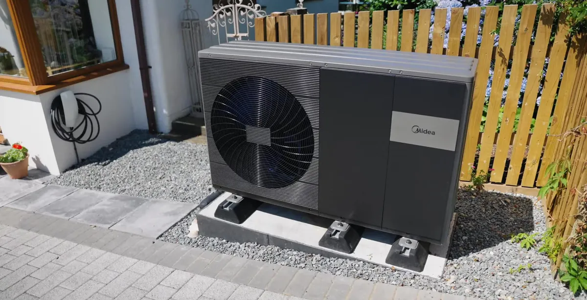 Midea air source heat pump outdoor unit on a gravel bed beside a white cottage, installed by Vanadium