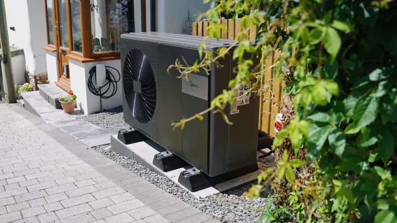 Heat pump outdoor unit next to the house with an EV charger on the wall