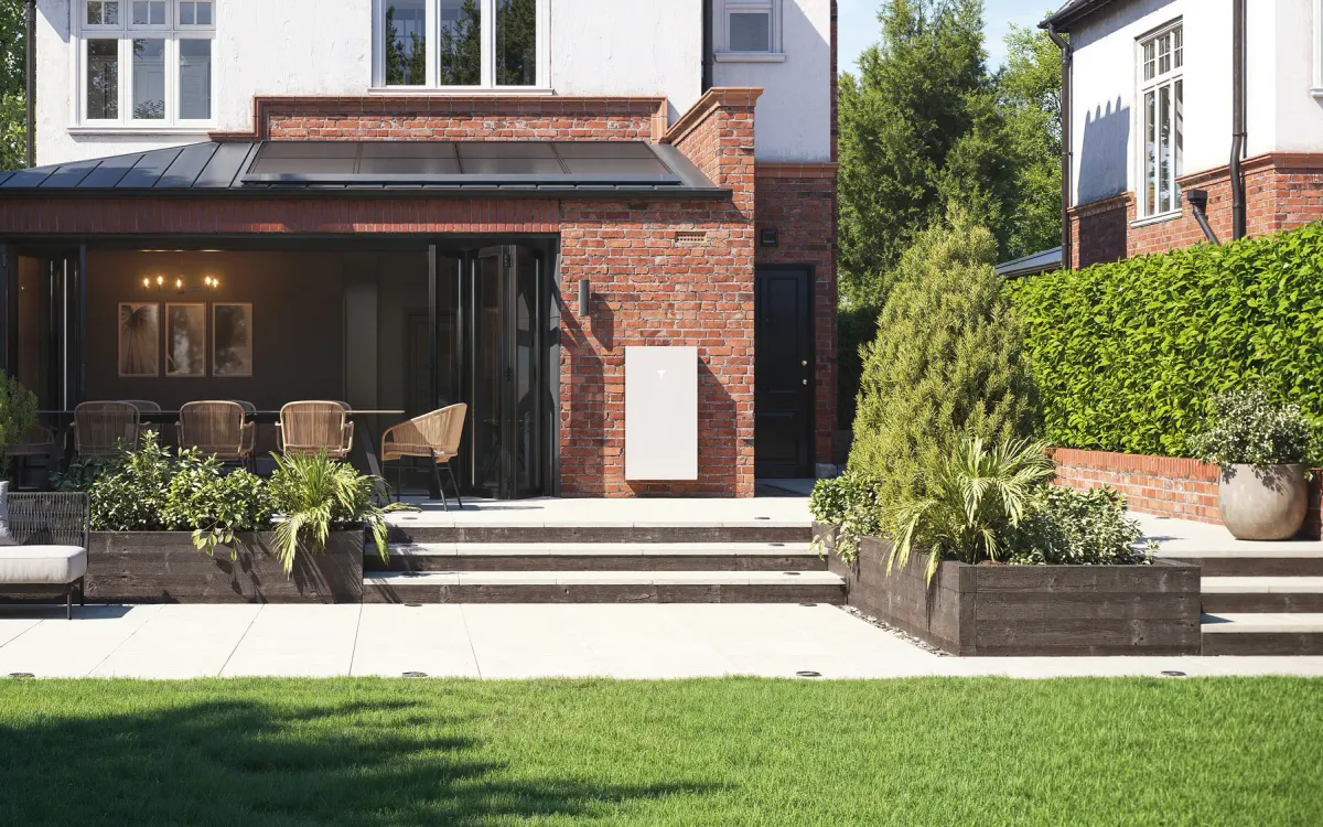 House extension with solar panels on the roof and a Tesla Powerwall 3 on the brick wall