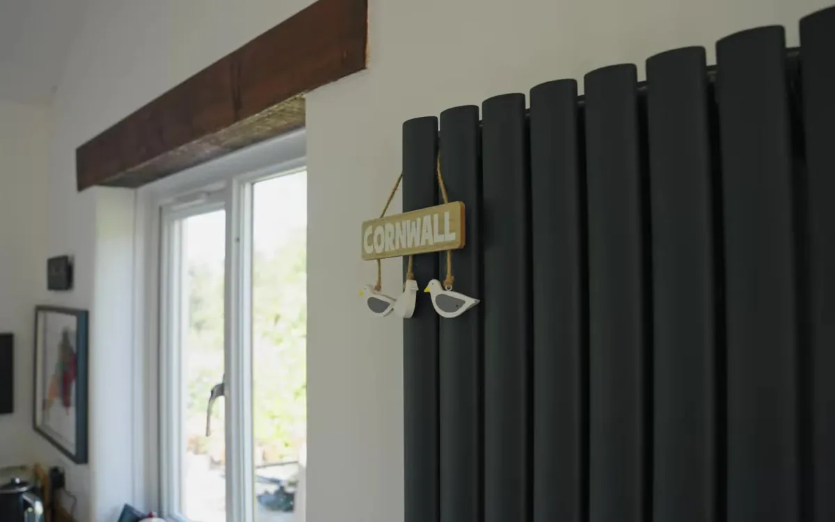 Tall anthracite radiator sized for a heat pump in a Cornish cottage