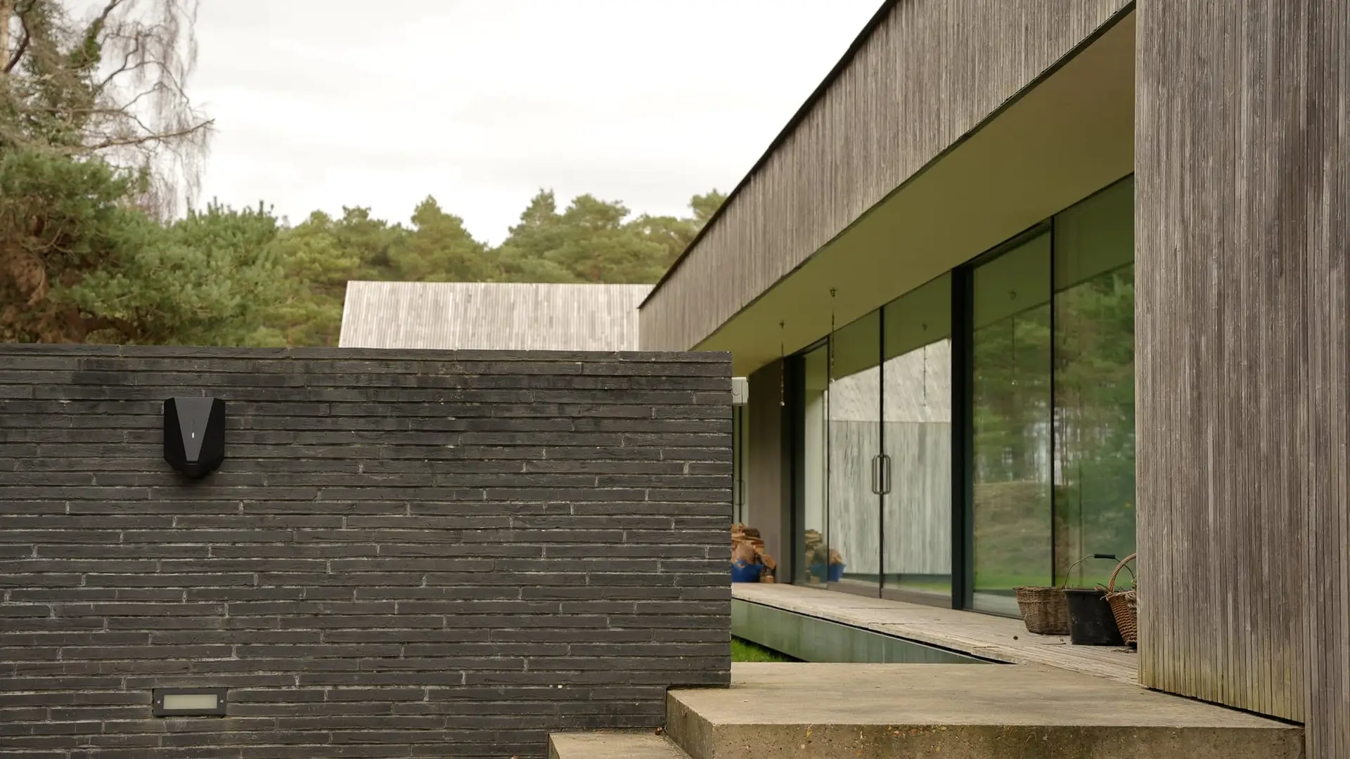 EV charger on the brick wall of a modern timber-clad home