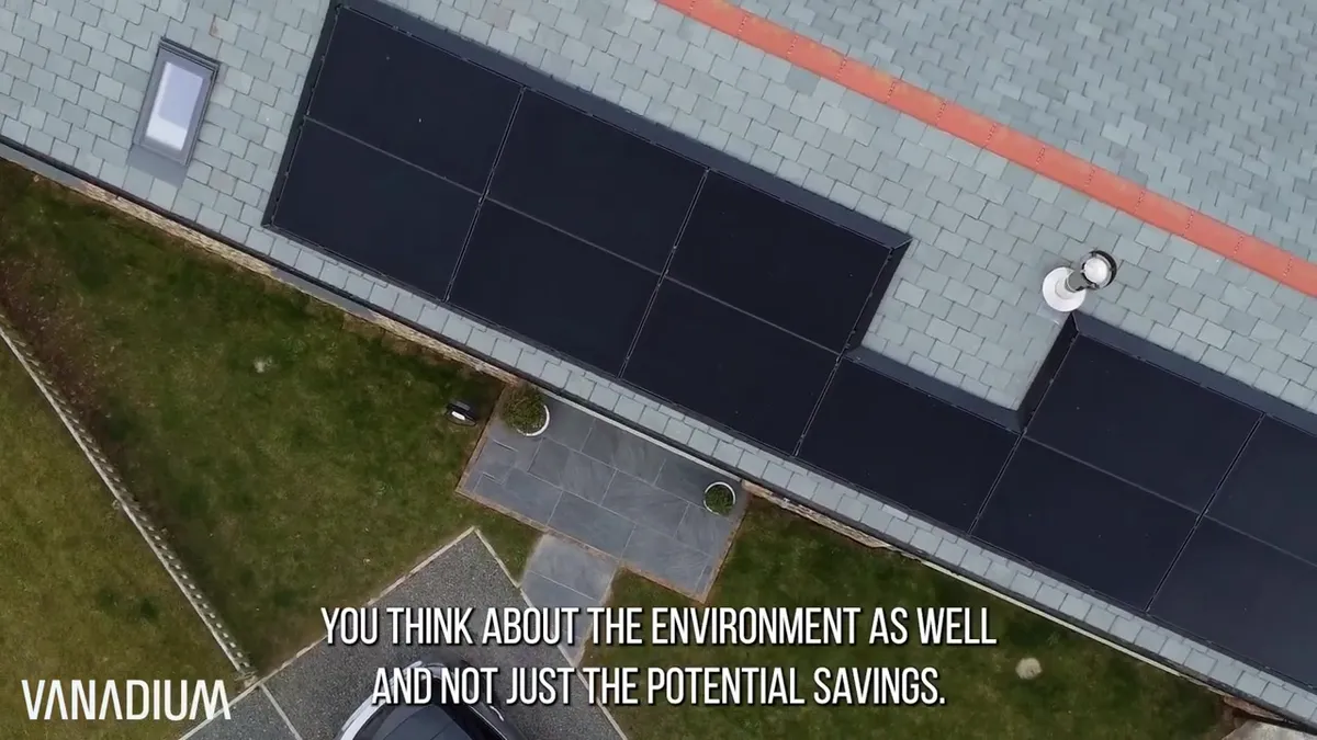 Overhead view of black solar panels neatly installed on a grey slate roof of a barn conversion.