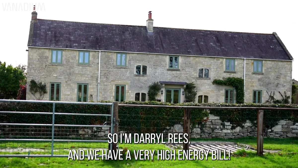 The homeowner speaking in front of his stone house and solar panels.