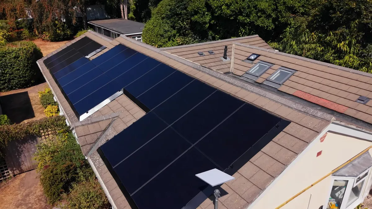 Aerial view of a house with black solar panels on the roof.