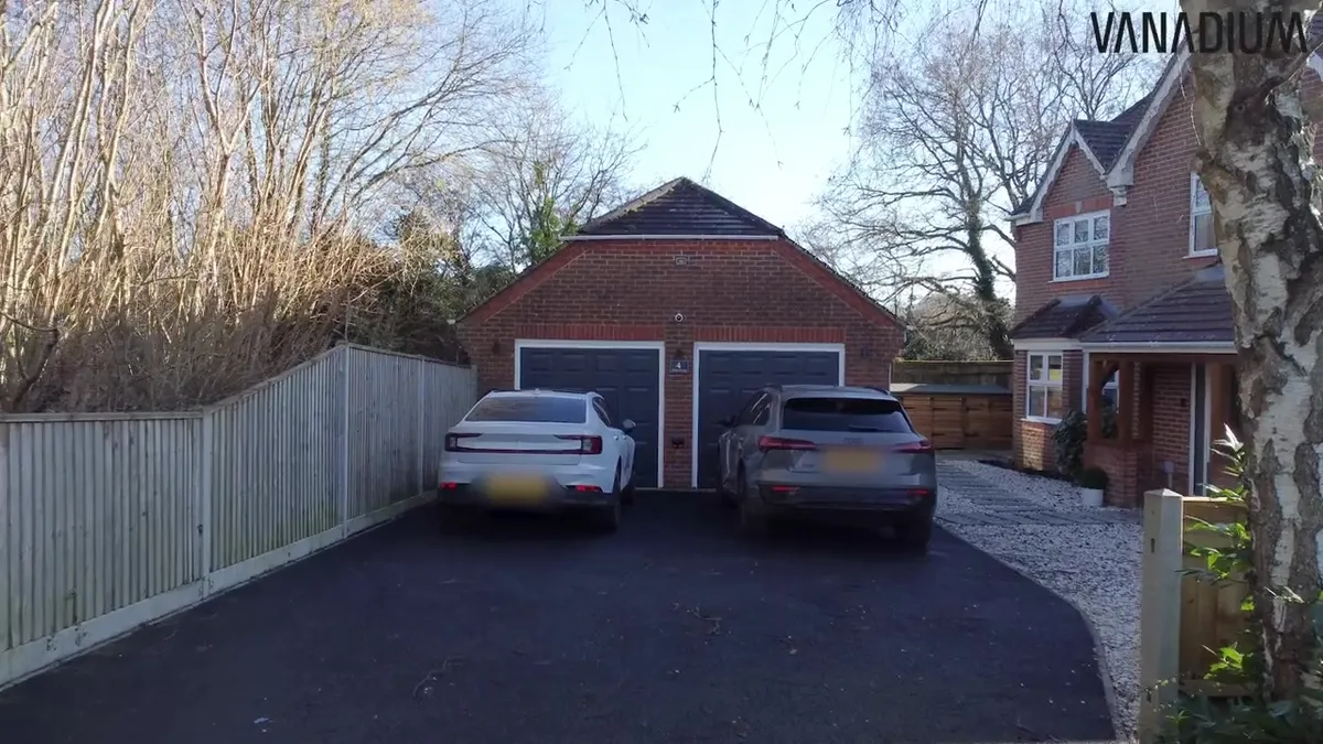 Two electric cars, a white Polestar and a grey Audi, parked in a driveway next to a brick garage.