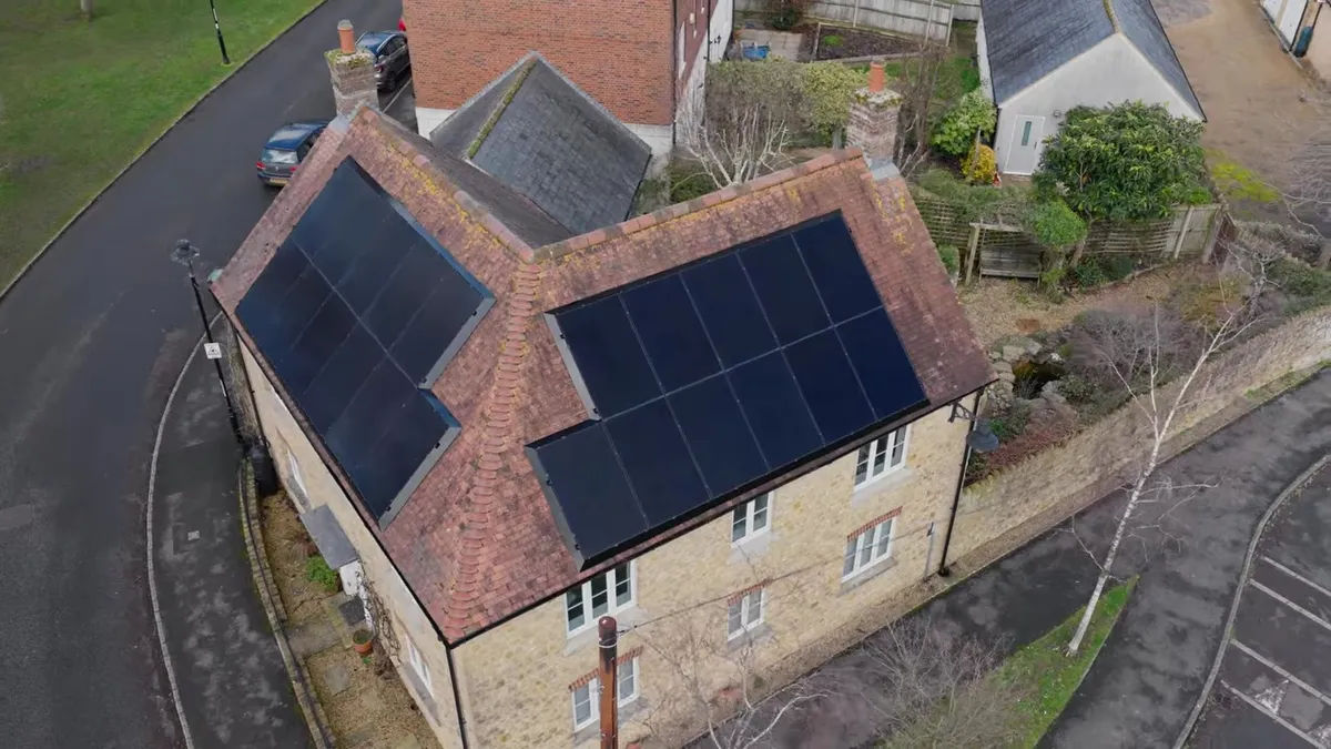 An aerial view of a house with solar panels on its roof.