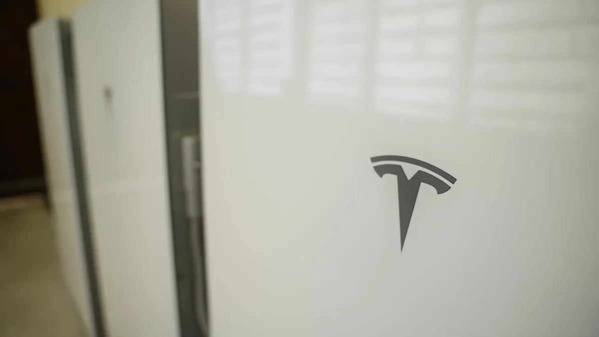Close-up of three white Tesla Powerwall units with the Tesla logo.