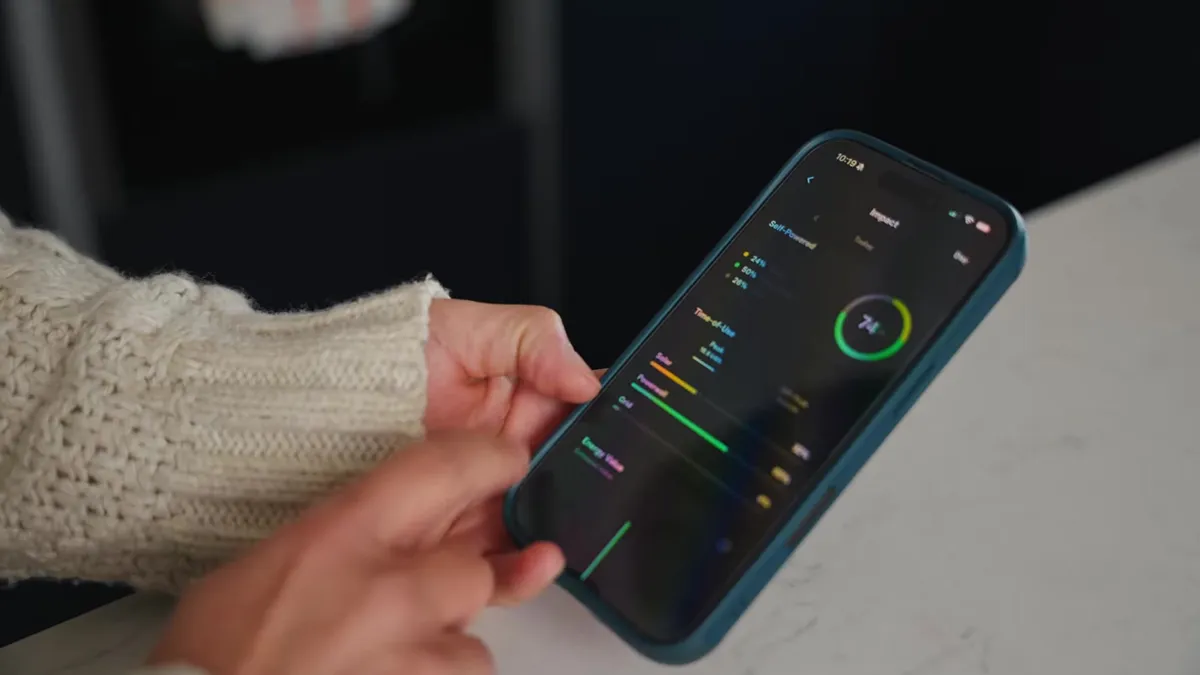 Close-up of a hand interacting with an energy monitoring app on a smartphone.