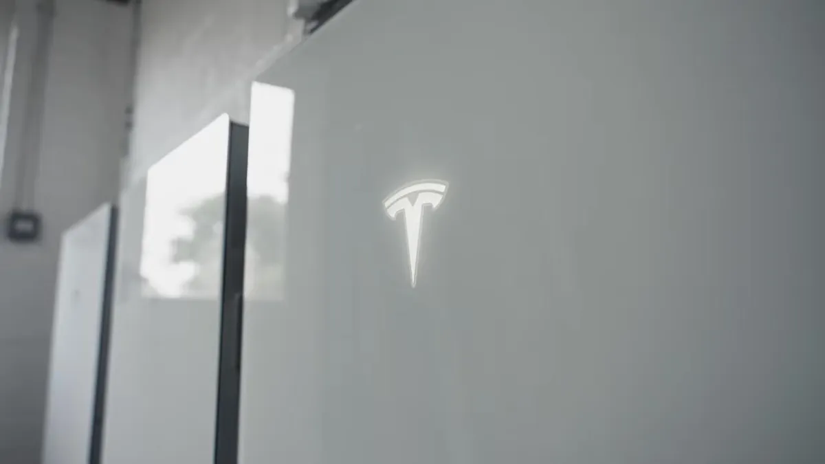 A Tesla Powerwall battery system is installed on a white wall.