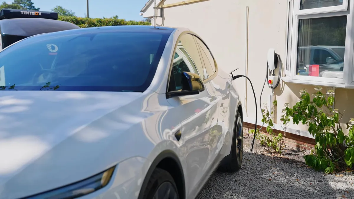White Tesla car charging at a home charging station.