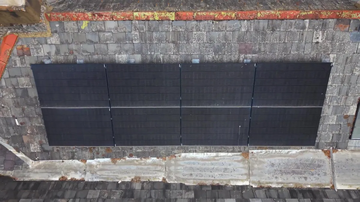 Two white Tesla battery units installed outside a black building.