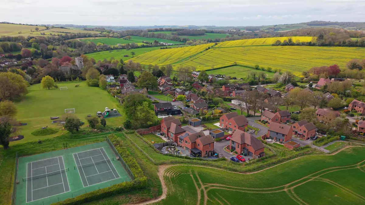 Aerial view of West Meon village with houses and green fields.
