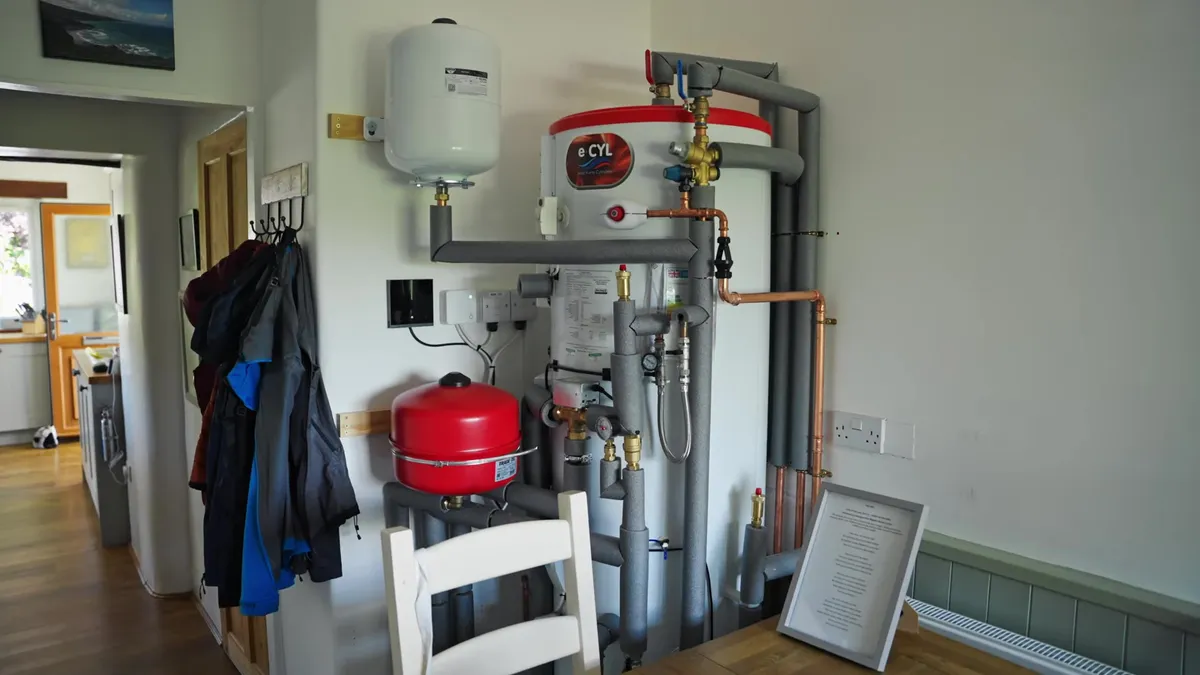 Interior view of a white eCYL heat pump cylinder with red and grey piping.