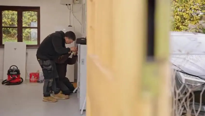 Two Vanadium installers working on the wiring and installation of the Tesla Powerwall 3 inside the garage.