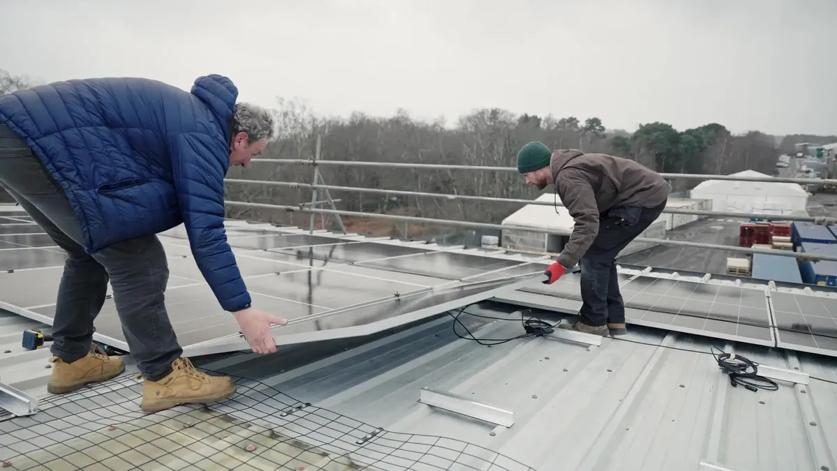 Two installers carrying a solar panel onto the roof of Modulift by Pewag