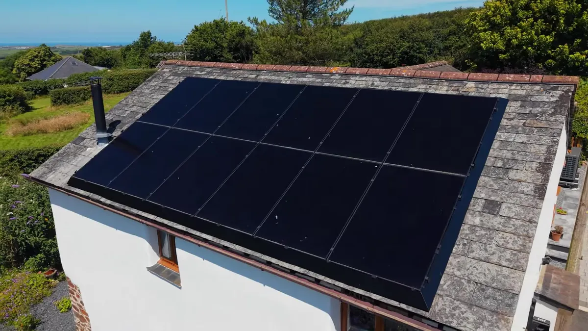 Solar panels are installed on the roof of a house with a chimney.