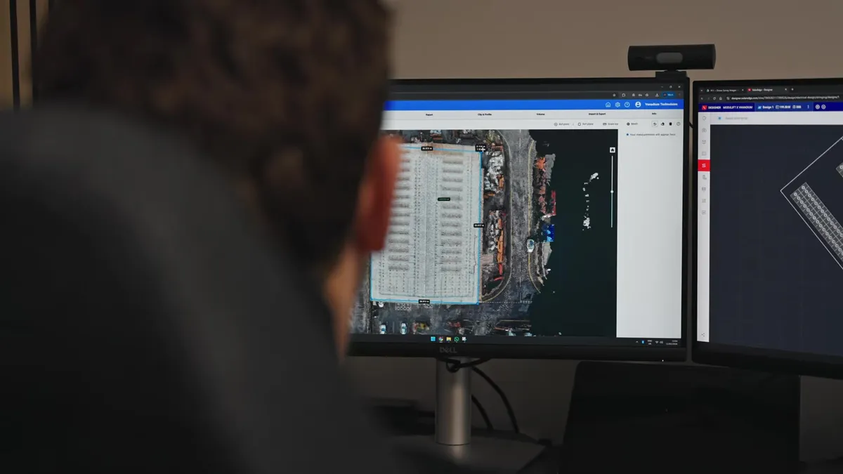 Vanadium designer laying out a commercial solar array on drone imagery, dual monitors