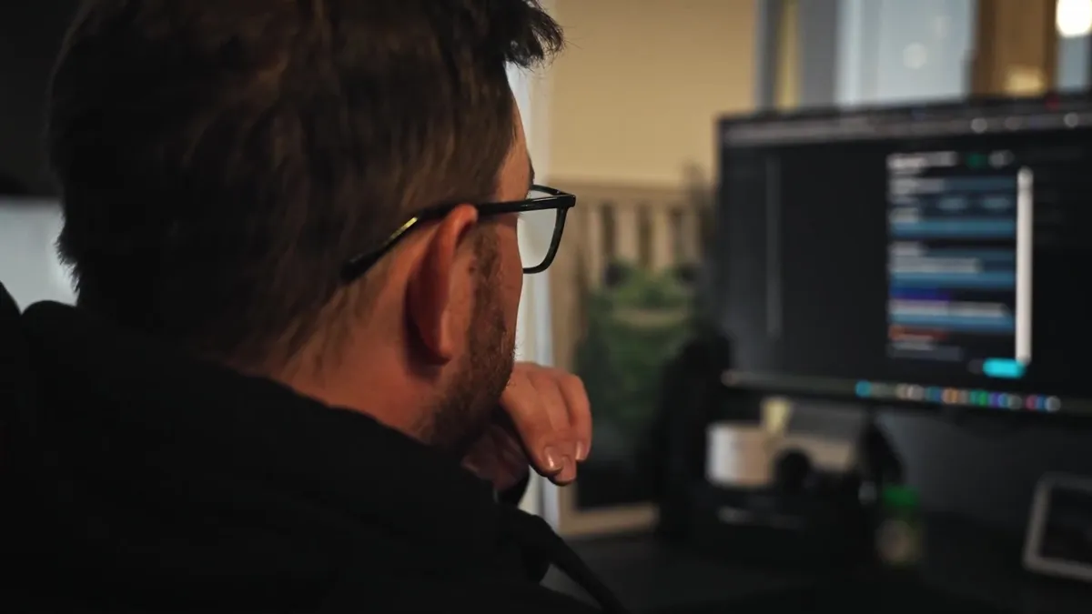 An engineer wearing glasses looks at a computer screen.