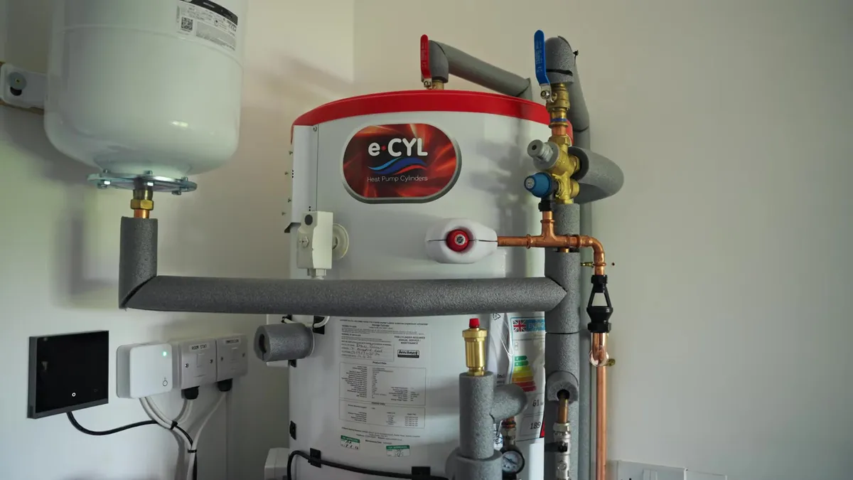 A heat pump cylinder and associated pipework are visible in a utility room.