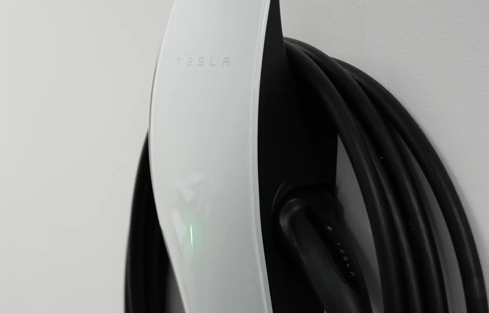 Tesla Wall Connector installed on a brick wall beside a Tesla